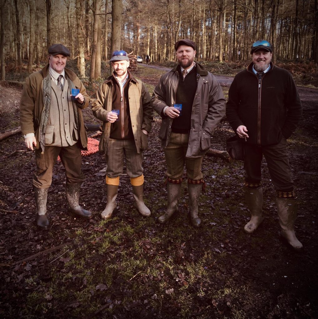 Four game hunters in boots and coats standing in the Staffordshire woodland, ready for their Pheasant Shooting experience.